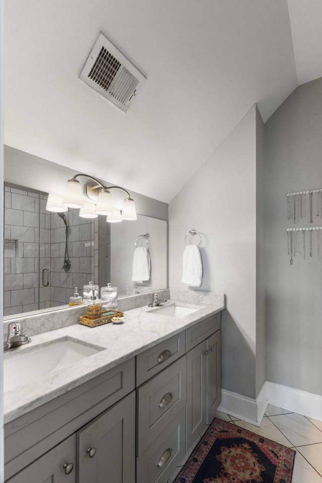 bathroom with vaulted ceiling, baseboards, a stall shower, and double vanity