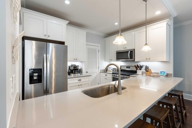 kitchen with appliances with stainless steel finishes, crown molding, a kitchen bar, white cabinets, and a sink