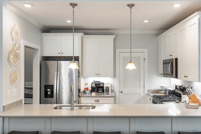 kitchen with appliances with stainless steel finishes, a peninsula, a sink, crown molding, and hanging light fixtures