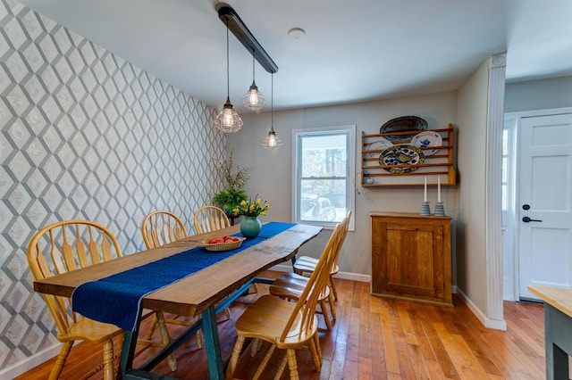 dining room with baseboards, an accent wall, and light wood finished floors