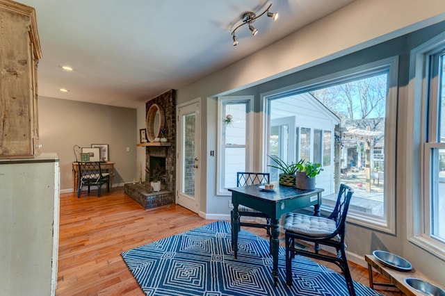 dining room with a fireplace, light wood-type flooring, and baseboards