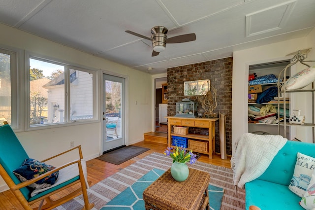 living room featuring baseboards, attic access, a ceiling fan, and wood finished floors