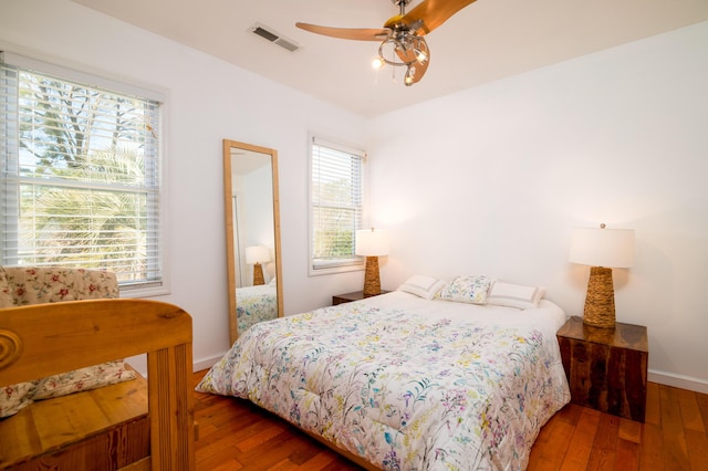 bedroom with a ceiling fan, baseboards, visible vents, and wood-type flooring