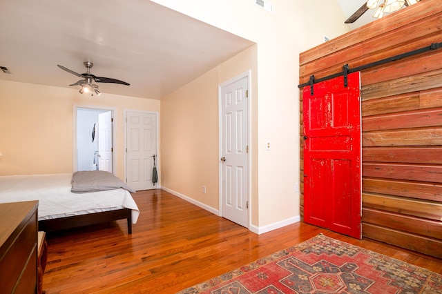 bedroom featuring visible vents, baseboards, a barn door, and wood finished floors