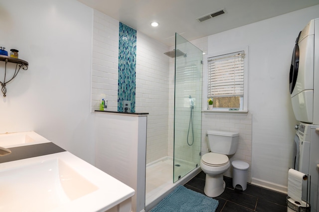 full bath with visible vents, tile patterned flooring, a walk in shower, stacked washer and clothes dryer, and toilet