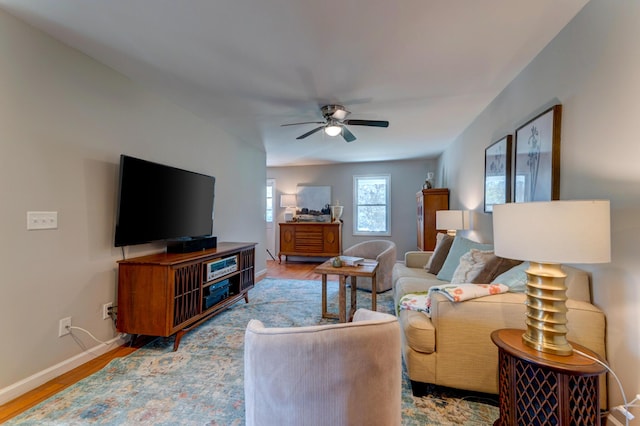 living area featuring wood finished floors, baseboards, and ceiling fan