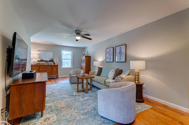 living area with a ceiling fan, wood finished floors, and baseboards