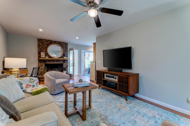 living area featuring wood finished floors, baseboards, recessed lighting, ceiling fan, and a brick fireplace