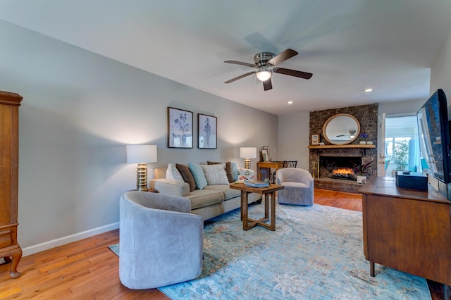 living room featuring wood finished floors, baseboards, a ceiling fan, a fireplace, and recessed lighting