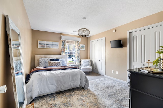 bedroom featuring a textured ceiling, carpet floors, and two closets