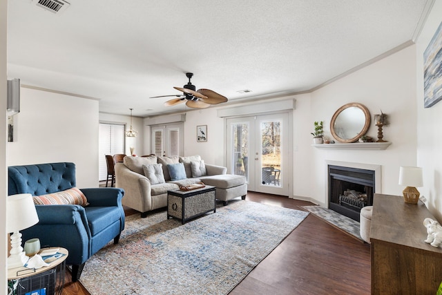 living room with french doors, ceiling fan, ornamental molding, a textured ceiling, and dark hardwood / wood-style flooring