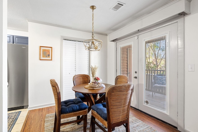 dining space with a notable chandelier, light wood-type flooring, and ornamental molding