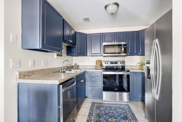 kitchen with sink, light tile patterned floors, blue cabinetry, a textured ceiling, and stainless steel appliances