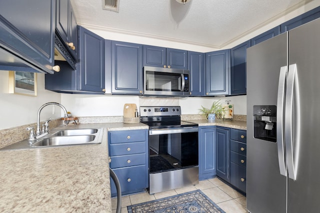 kitchen featuring a textured ceiling, stainless steel appliances, blue cabinets, sink, and light tile patterned floors