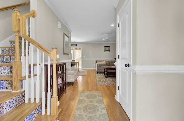 corridor featuring recessed lighting, wood finished floors, baseboards, ornamental molding, and stairway