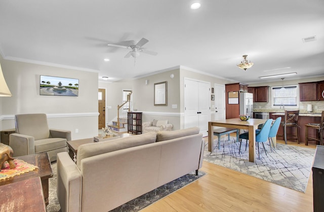 living area with recessed lighting, visible vents, ornamental molding, light wood-type flooring, and stairs