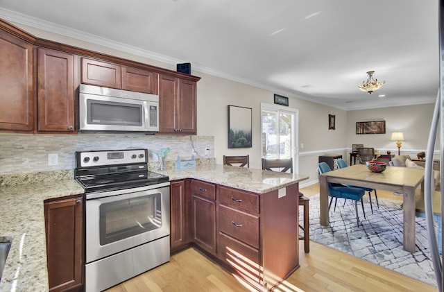 kitchen with a peninsula, light wood-type flooring, appliances with stainless steel finishes, and ornamental molding