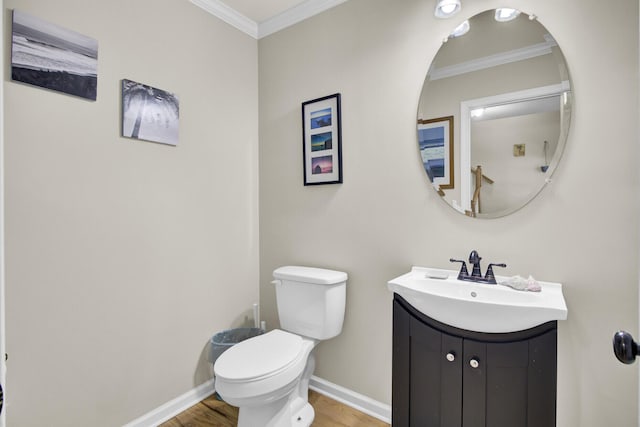 bathroom featuring toilet, wood finished floors, vanity, baseboards, and crown molding