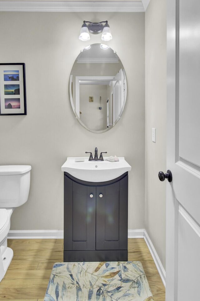 half bath featuring toilet, baseboards, ornamental molding, and wood finished floors