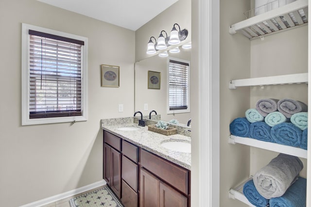 bathroom with double vanity, baseboards, and a sink