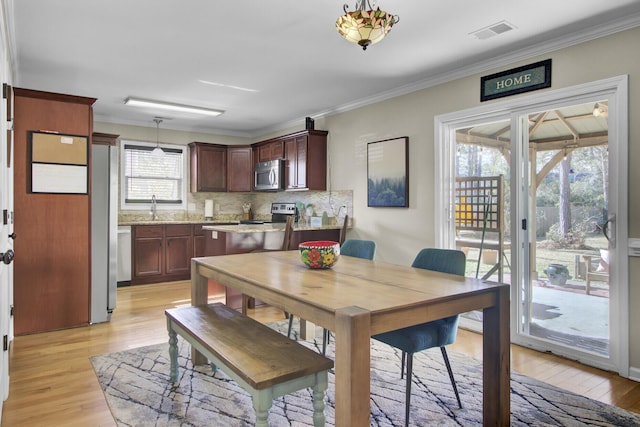 dining space with ornamental molding, visible vents, and light wood finished floors