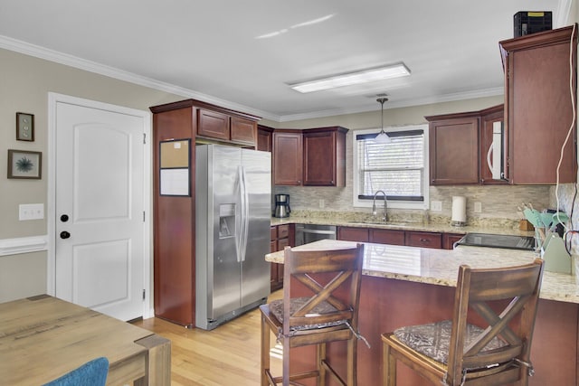 kitchen with light stone counters, stainless steel appliances, a sink, dark brown cabinets, and a peninsula