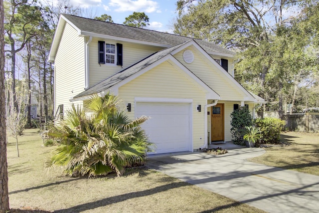 traditional home with roof with shingles, driveway, an attached garage, and fence