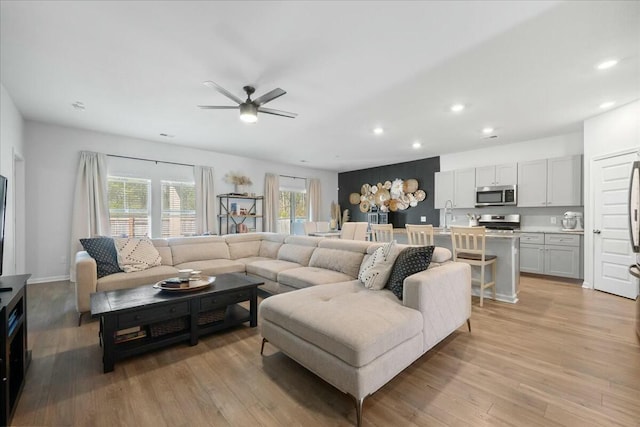 living room featuring baseboards, recessed lighting, a ceiling fan, and light wood-style floors