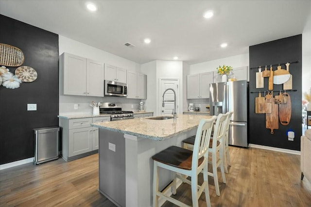 kitchen featuring stainless steel appliances, a breakfast bar, a sink, visible vents, and light wood-type flooring