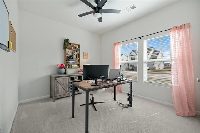 office space with a ceiling fan, visible vents, light carpet, and baseboards