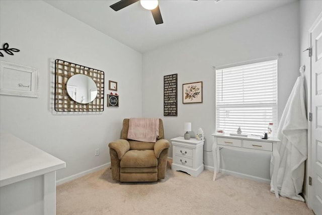 living area with light carpet, baseboards, and a ceiling fan