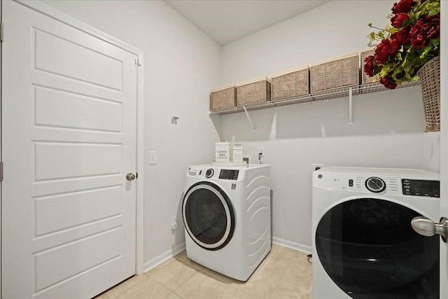 washroom with laundry area, separate washer and dryer, light tile patterned flooring, and baseboards