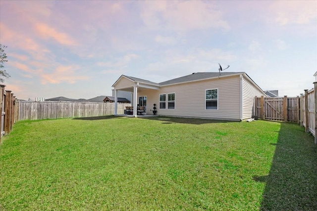 back of house featuring a fenced backyard, a lawn, and a patio