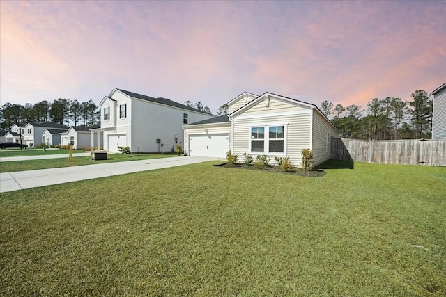 view of front of home with concrete driveway, an attached garage, fence, cooling unit, and a front yard