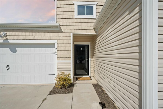 view of exterior entry featuring concrete driveway and an attached garage