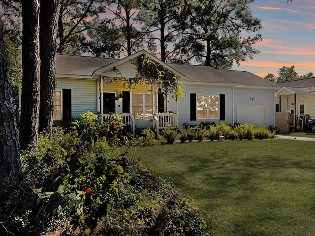 ranch-style house featuring a garage, a yard, and covered porch