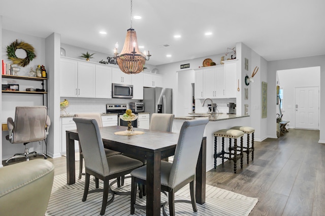 dining space featuring wood-type flooring, sink, and an inviting chandelier