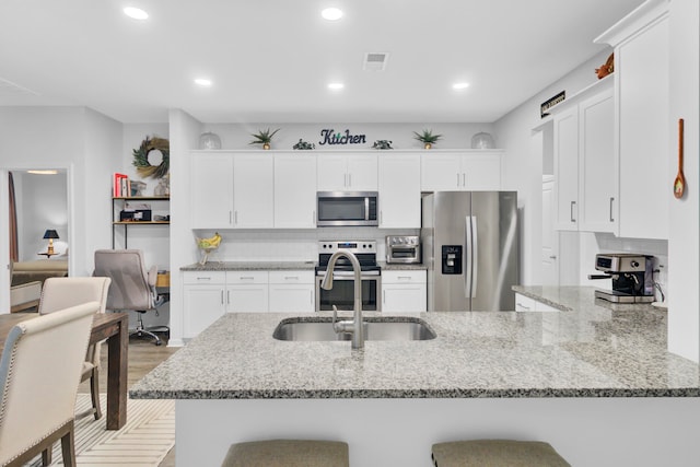 kitchen with kitchen peninsula, appliances with stainless steel finishes, a breakfast bar area, and white cabinets