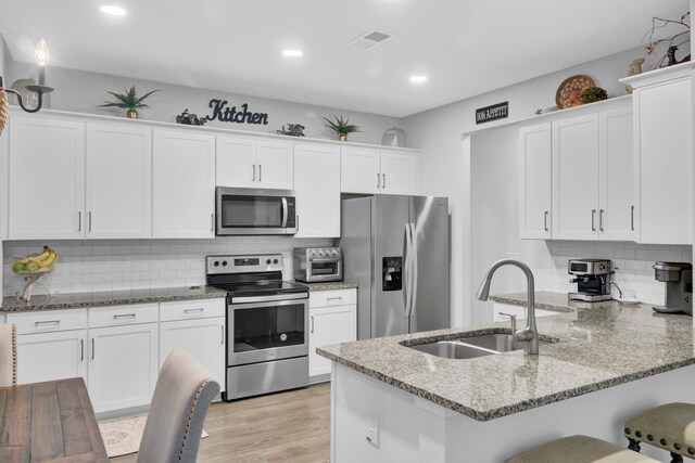 kitchen with stainless steel appliances, light wood-type flooring, white cabinetry, sink, and kitchen peninsula