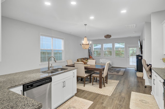 kitchen with dark stone counters, white cabinetry, stainless steel dishwasher, and sink