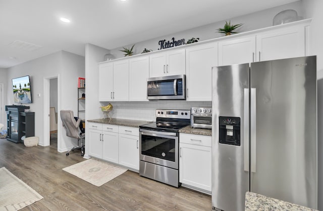 kitchen with stainless steel appliances, white cabinets, hardwood / wood-style floors, backsplash, and light stone countertops