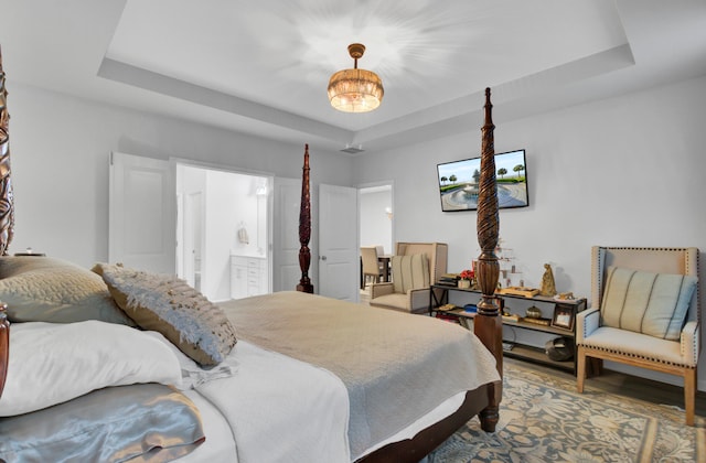 bedroom featuring connected bathroom and a tray ceiling