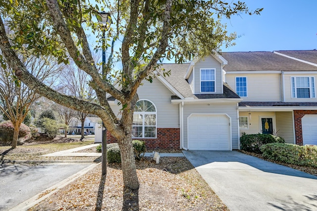 townhome / multi-family property featuring concrete driveway, brick siding, and a shingled roof