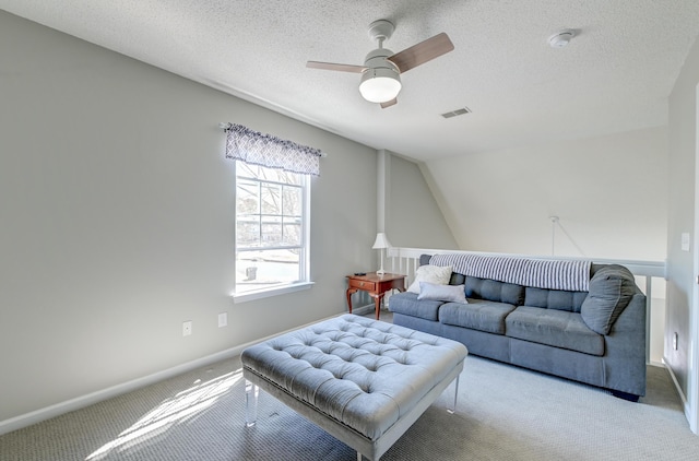 living area featuring a textured ceiling, carpet flooring, a ceiling fan, visible vents, and baseboards