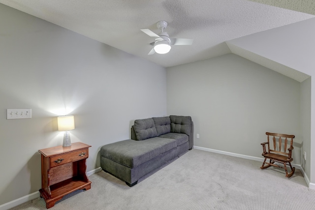 living area featuring baseboards, lofted ceiling, ceiling fan, carpet, and a textured ceiling