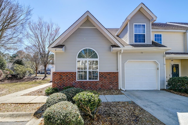 traditional-style house featuring an attached garage, roof with shingles, concrete driveway, and brick siding