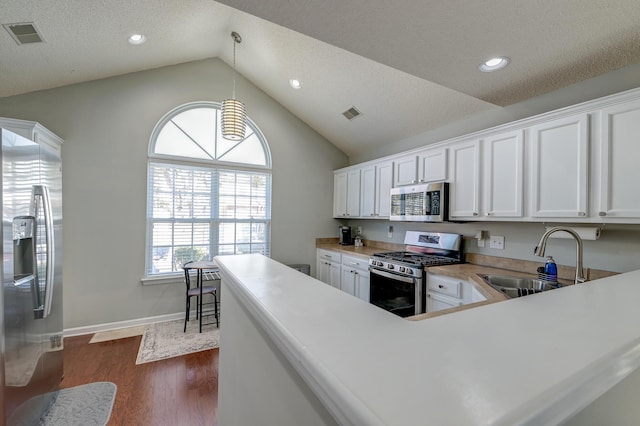 kitchen with dark wood-style floors, vaulted ceiling, stainless steel appliances, white cabinetry, and a sink