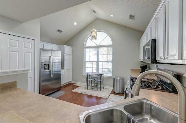 kitchen featuring stainless steel appliances, a sink, visible vents, and white cabinetry