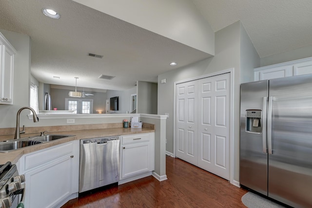 kitchen with stainless steel appliances, white cabinetry, a sink, and a peninsula