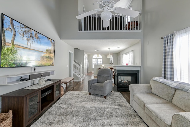 living room with stairs, dark wood-style flooring, a multi sided fireplace, and a towering ceiling